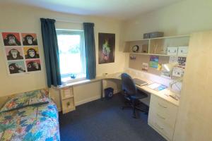 Image of a en-suite large modern room at ffriddoedd, with a bed, desk, chair and storage