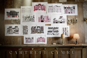 Still from the opening titles of 'Cartrefi Cymru' with colourful illustrations of houses from different periods displayed on a wooden panelled wall.