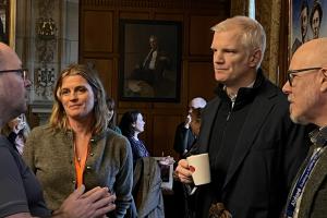 Image of three men and one woman chatting informally at an event