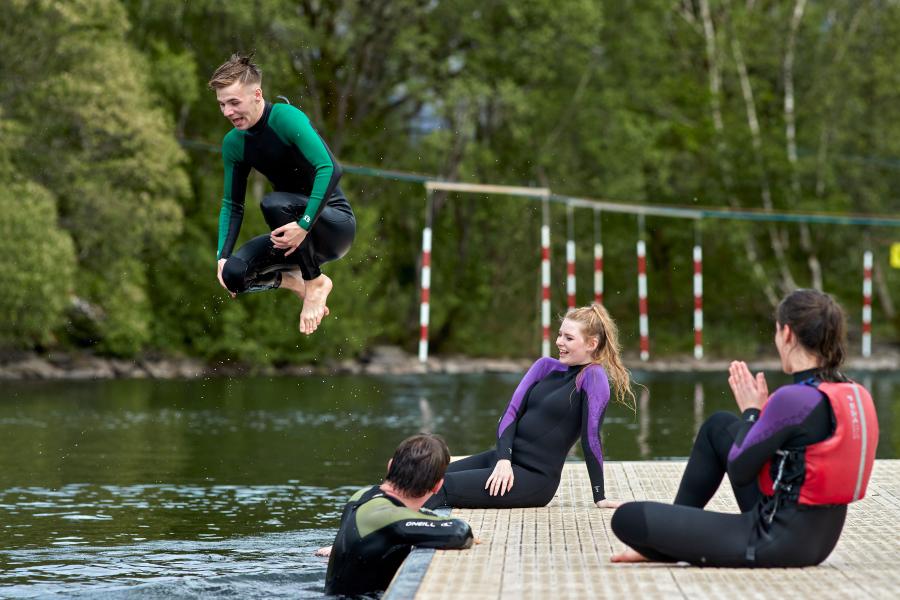 Students in their wetsuits diving in to Llyn Padarn lake at nearby Llanberis