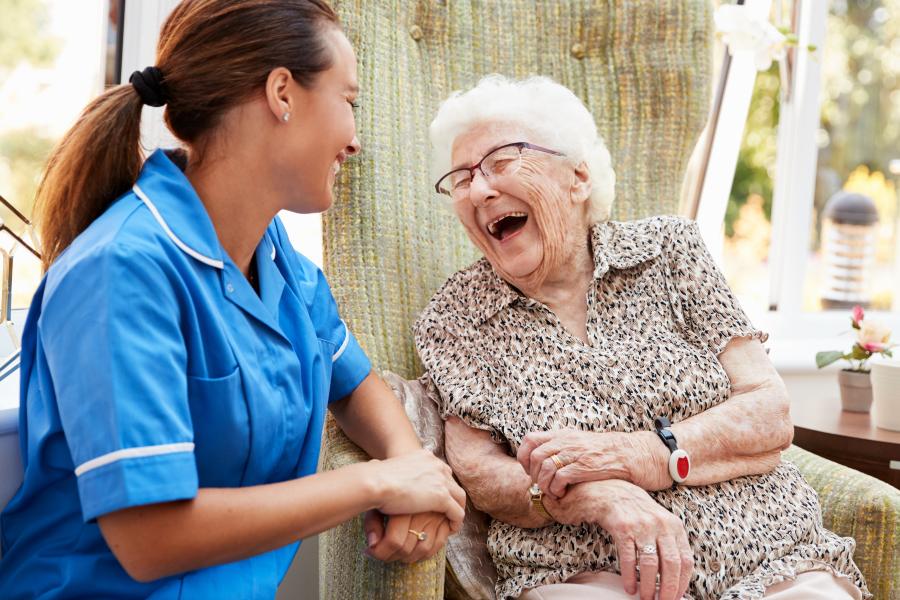 Woman sitting in a chair and talking to a nurse in a nursing home