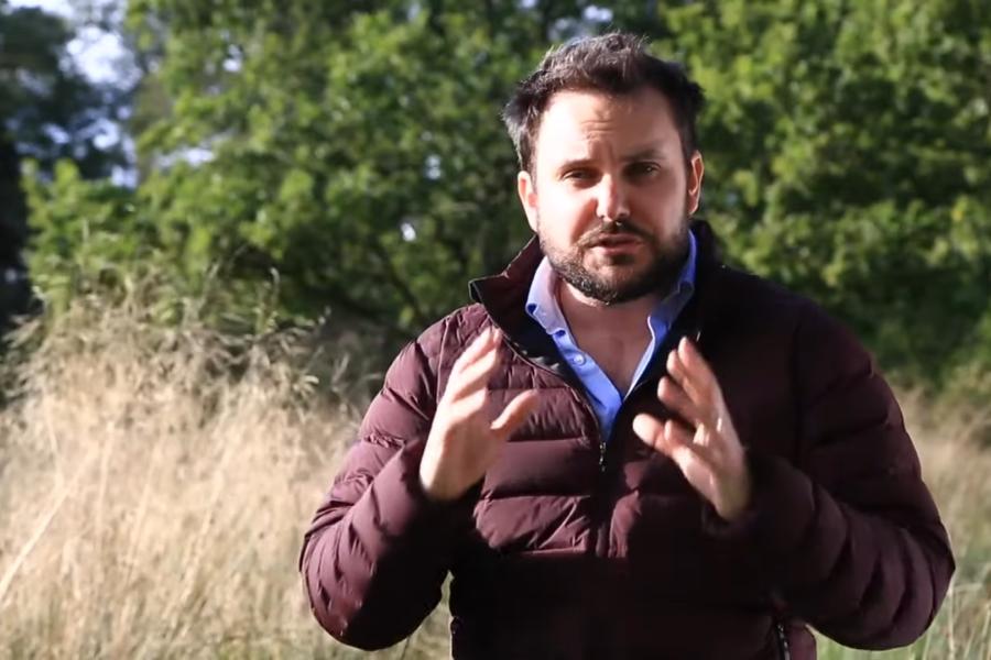 Mab standing in  field speaking and using his hands