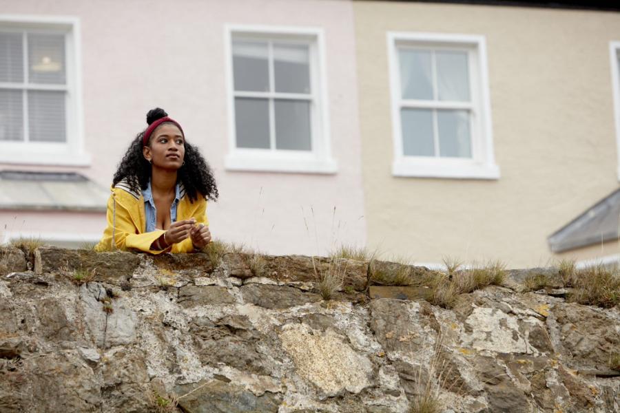 A student leans up against a wall in front of beach-front houses at Beaumaris