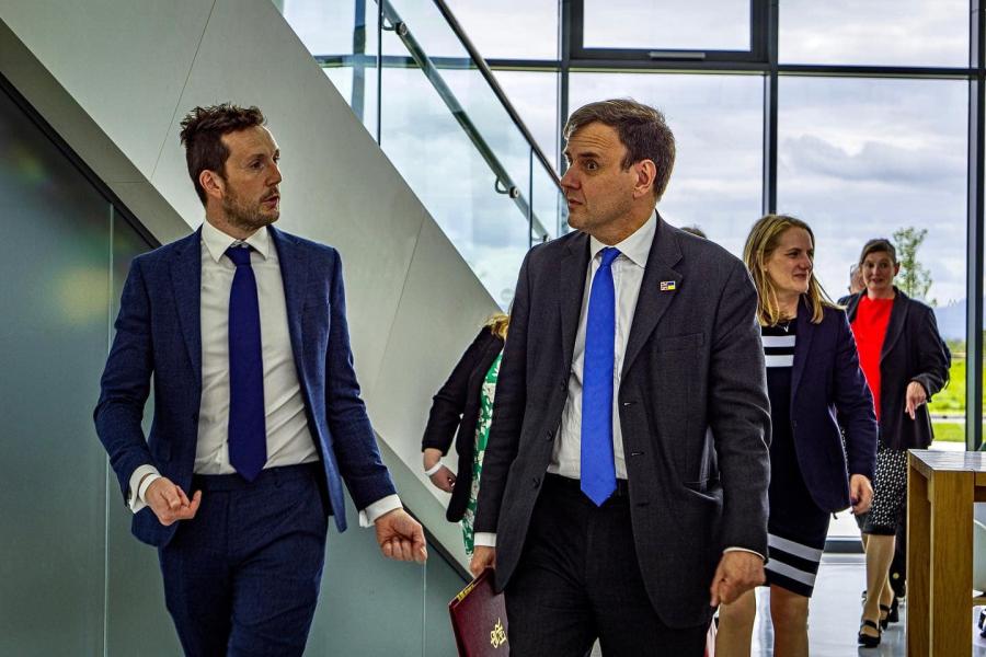 two people  stride towards the camera inside a glass walled M-Sparc Science Park.