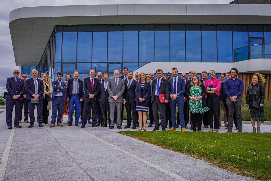 A large group of delegates stand outside the M Sparc building