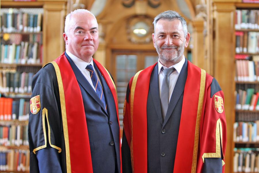 two men in academic gowns in a library