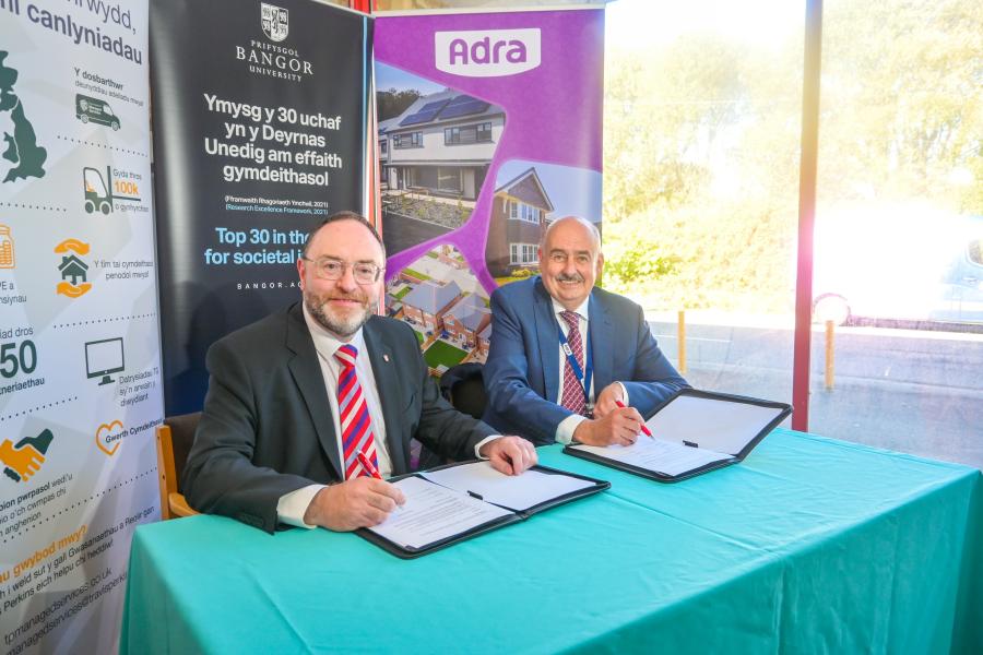 two males in suits signing a document