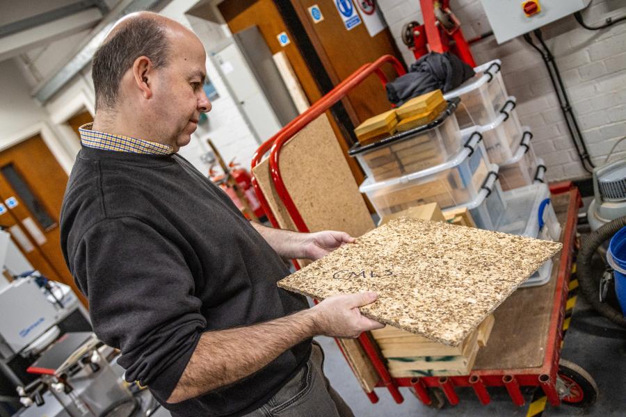 Man in industrial setting looks at composite board.