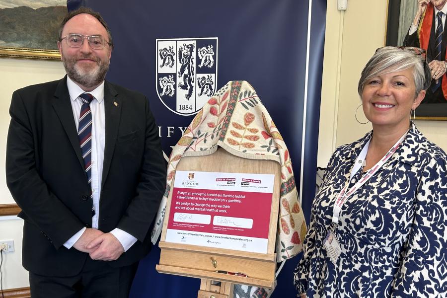 Man and woman standing alongside a board which makes a pledge to tackle stigma around mental health