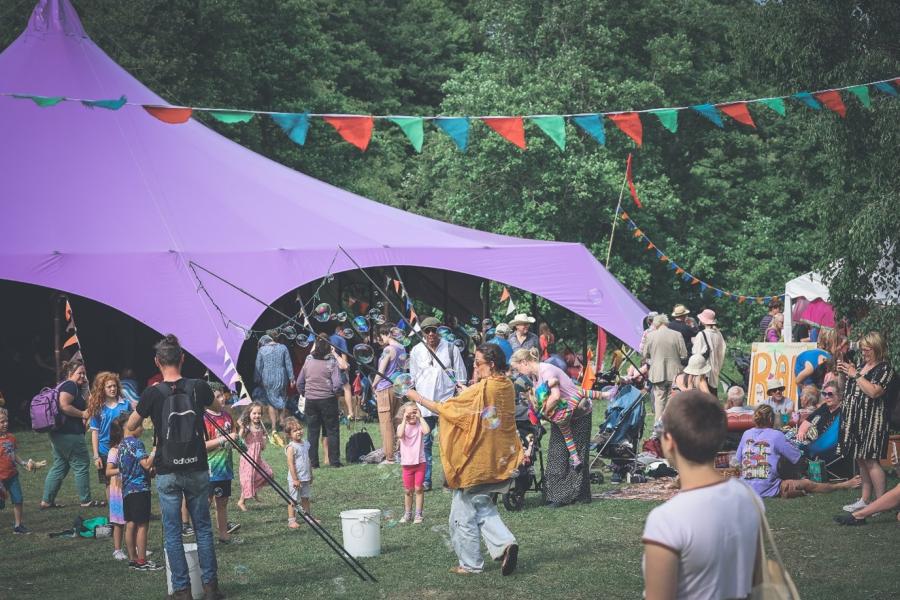 People in a festival with a purple marquee and bunting