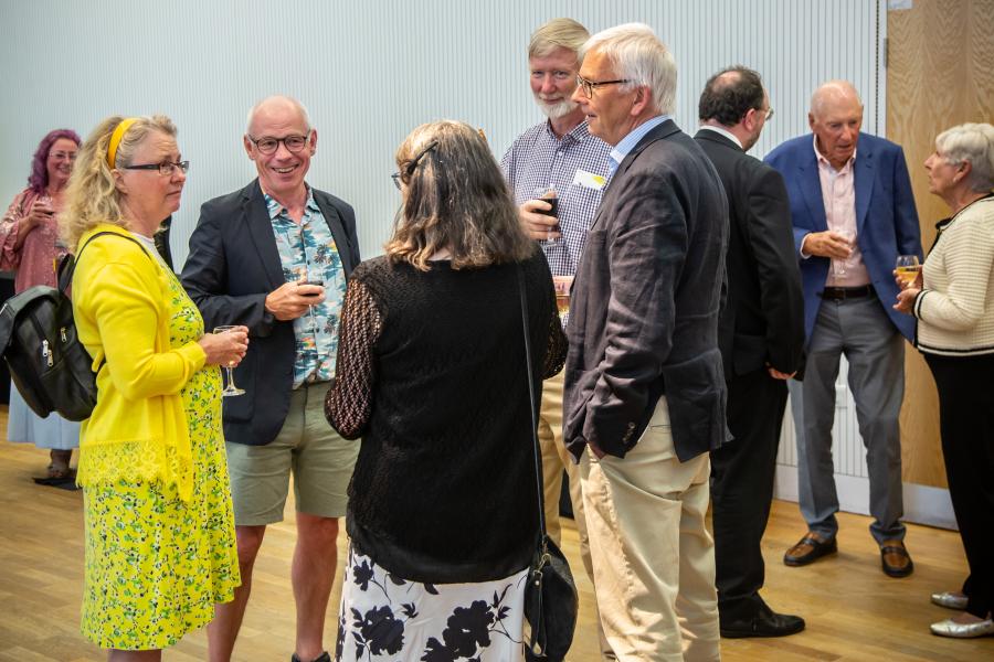 Grwp o gyn-fyfyrwyr yn siarad yn y derbyniad / A group of alumni chatting during the reception