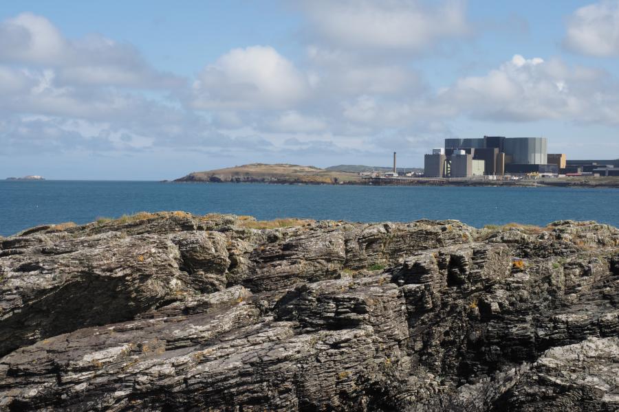 Gorsaf Ynni Niwclear Wylfa o Fae Cemaes ar Ynys Môn, gyda chreigiau yn y blaendir