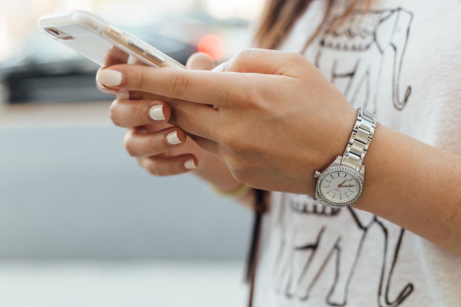 Hands with white painted nails holding a mobile phone