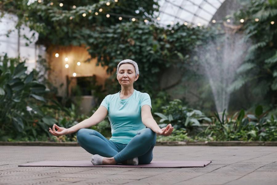 Woman engaged in meditation surrounded by green plants