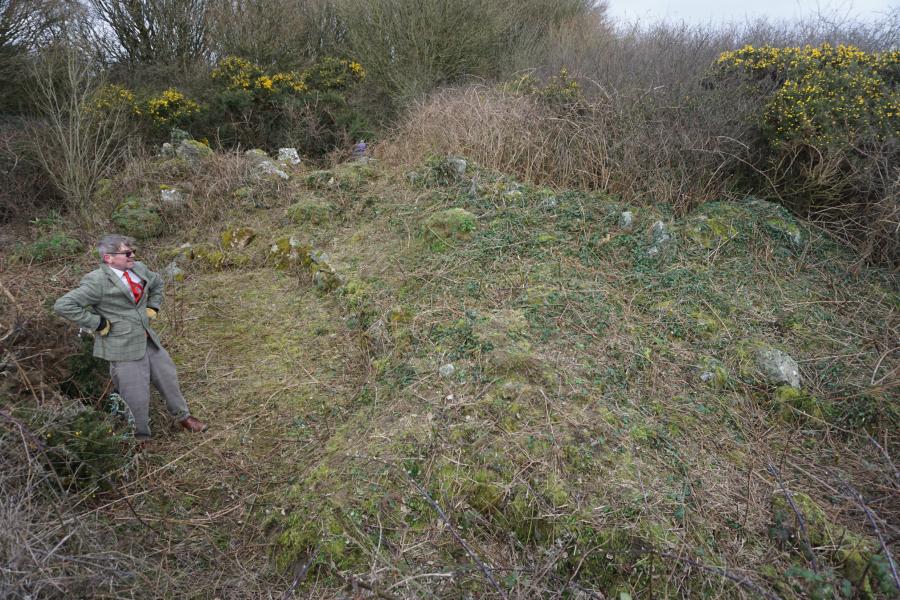 A man in tweeds surveys an overgrown part of the Map of wales.