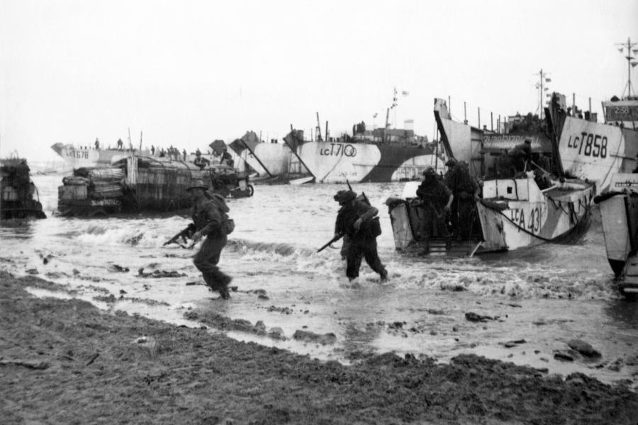 Black and white image of troops wading ashore from landing craft