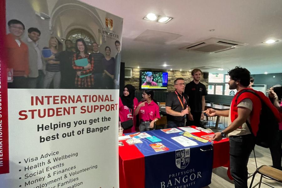 International Student Support staff behind a table with a banner at Bar Uno