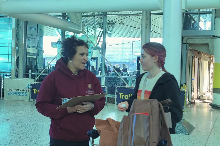 Image of two students with suitcases at an airport