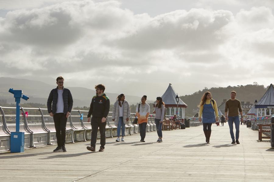 A group of students walking along Garth Pier in Bangor