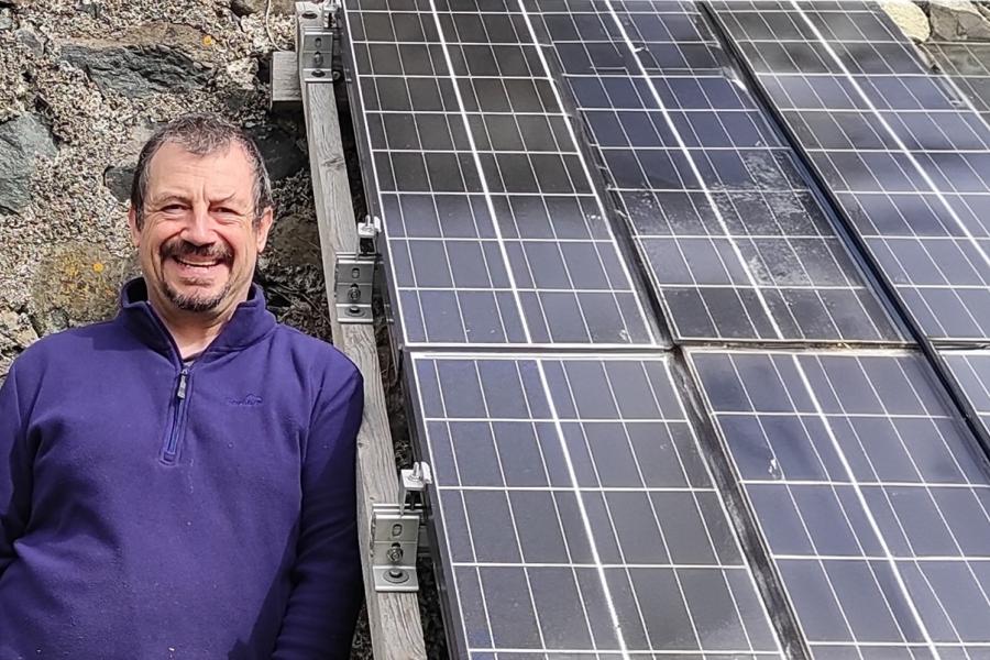 Dr Noel Bristow alongside a roof set of solar panels 