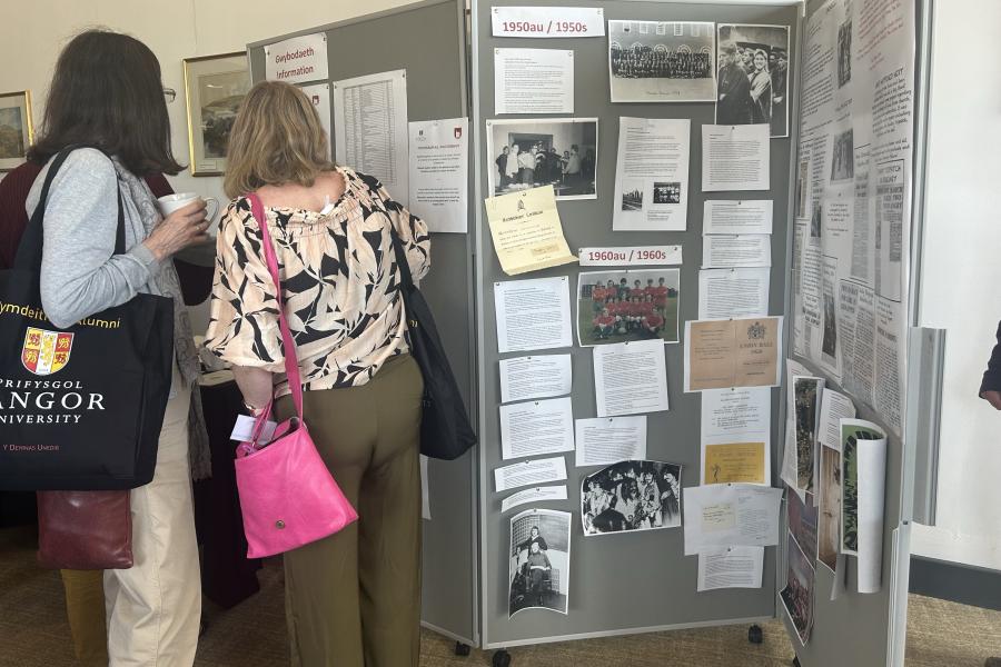 Two alumni looking at boards of alumni memories