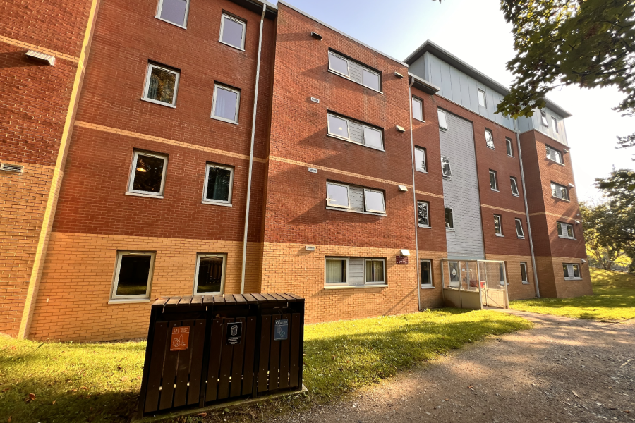 4 floored building surrounded by greenery, fasade in brown, dark brown and white