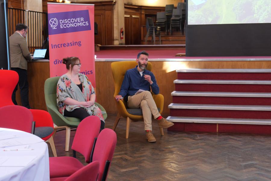 Sam from discover economics talking whilst sitting on a coloured chair 