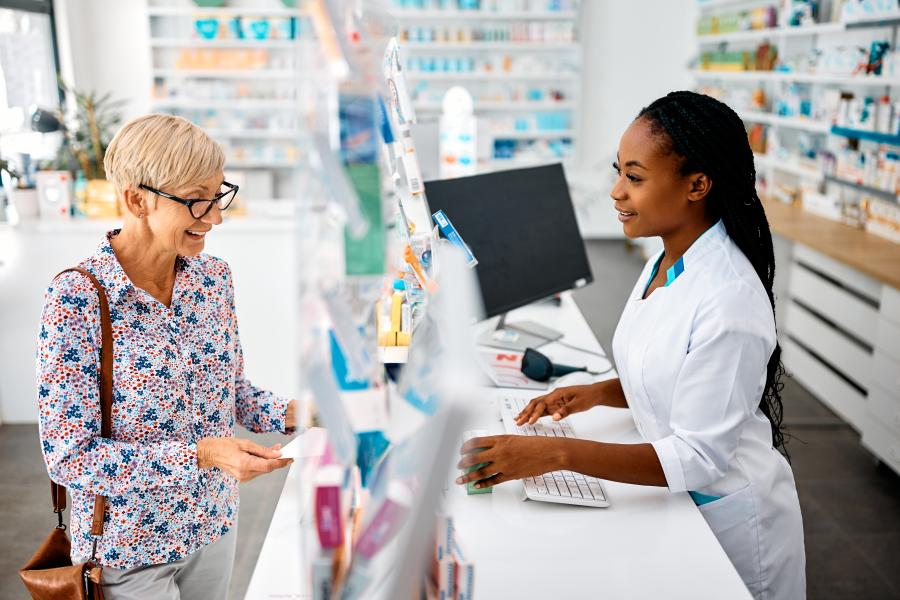 a senior woman is in a pharmacy being helped by a young pharmacist at the counter