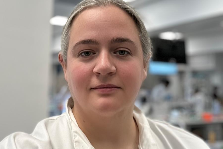 Bethan Davies-Jones a female lecturer is wearing a lab coat standing in a laboratory