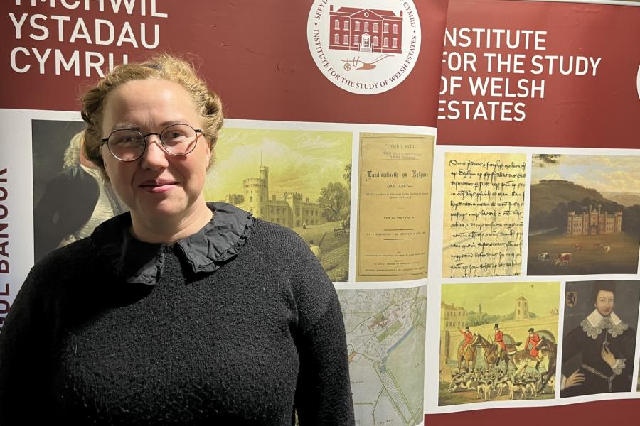 A photograph of doctoral student Daisy Hughes standing in front of the ISWE banner