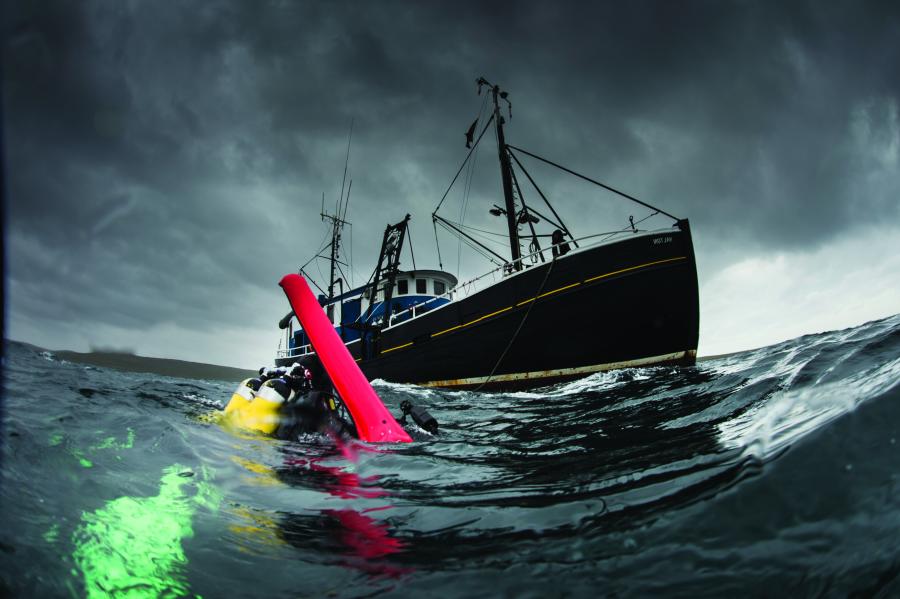 Research being conducted at sea with vessel in the background