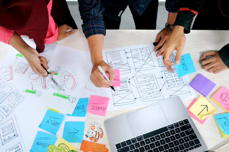 People working on a project on a desk with sticky notes and laptop