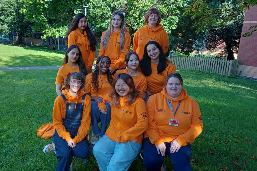 Image of ten Campus Life Coordinators posing for a group photo, all wearing their signature orange hoody.