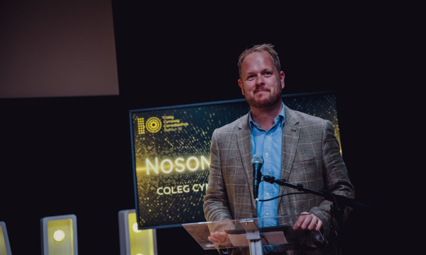 Photo of Dr Llŷr Roberts at a loectern in an awards ceremony