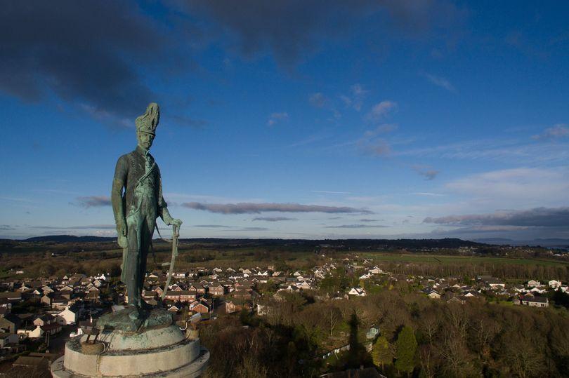 Ffotograff o Golofn Ardalydd Ynys Mon gyda olygfa o'r tirwedd yn y cefndir