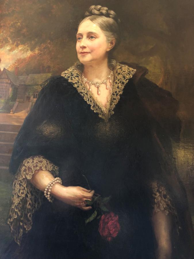 A portrait of a woman wearing a black gown with lace trims.