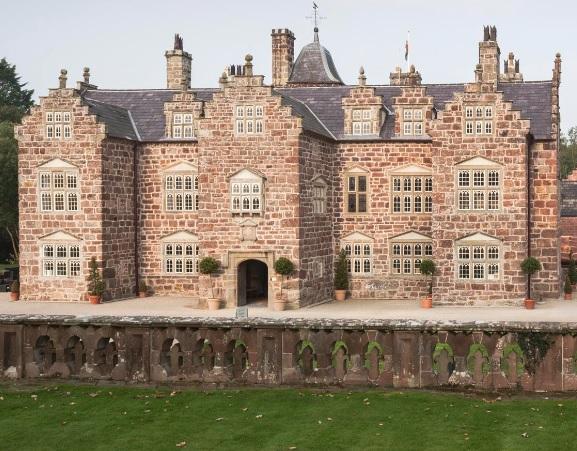 Plas Coch, a redstone mansion with a symmetrical facade, crow-stepped gables, and pediments above each window. 