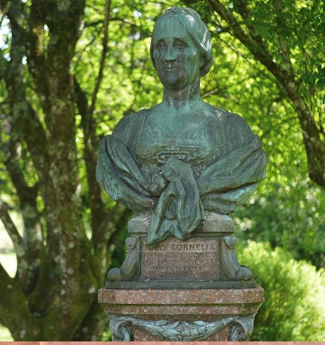 Photograph of a statue of a woman mounted in a woodland.